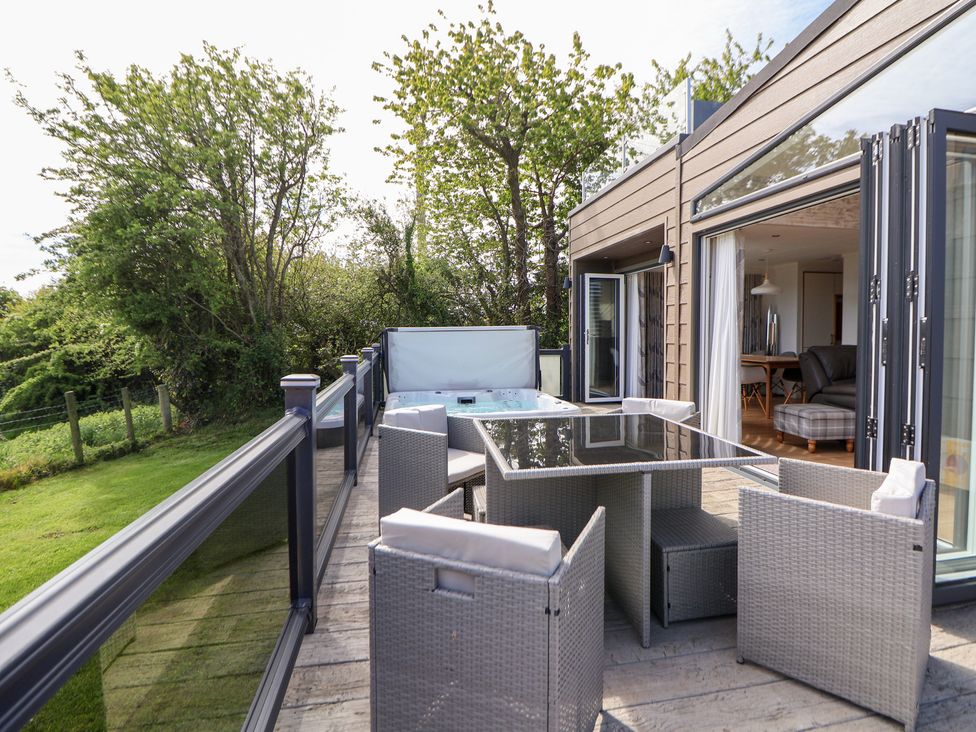 An outdoor patio with seating and a hot tub at The Lodge @ Racecourse House in Babell near Holywell