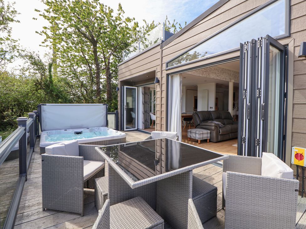 An outdoor patio with a hot tub and dining table at The Lodge @ Racecourse House in Babell near Holywell