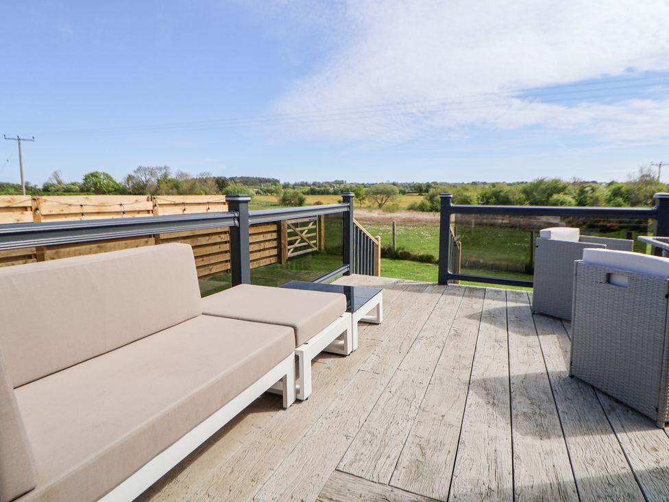 An outdoor seating area with a sofa on a deck at The Lodge @ Racecourse House Babell near Holywell