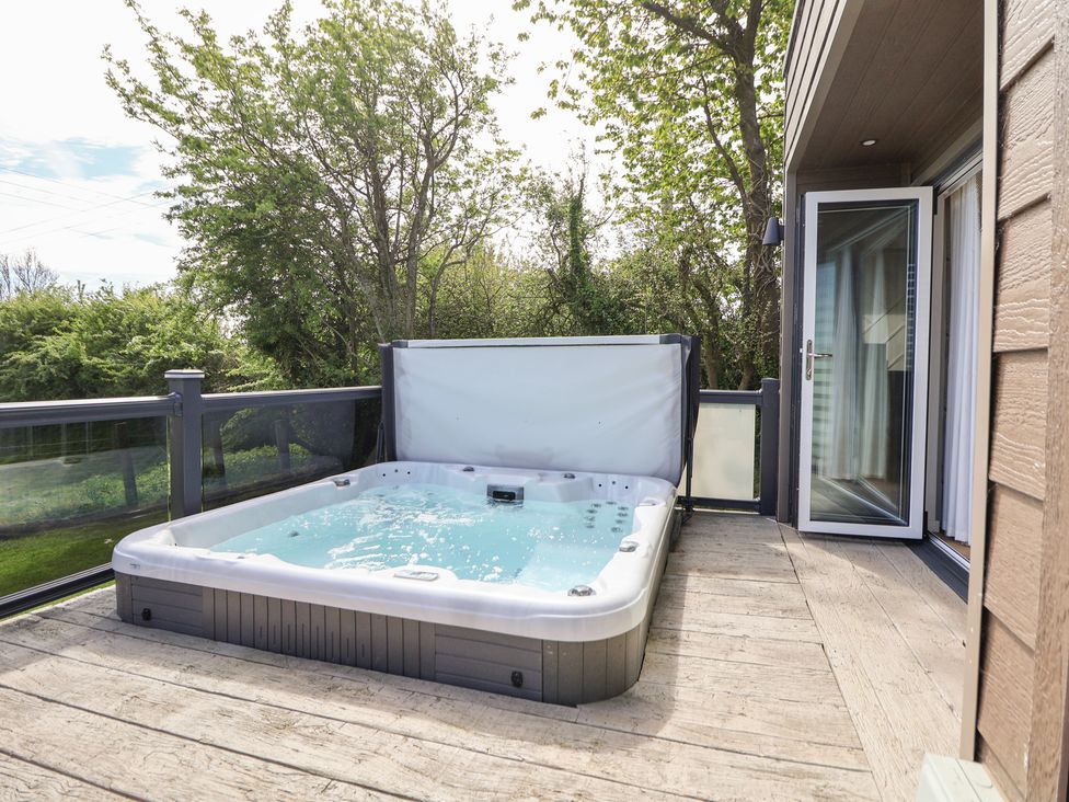An outdoor area with a hot tub and deck at The Lodge @ Racecourse House near Holywell