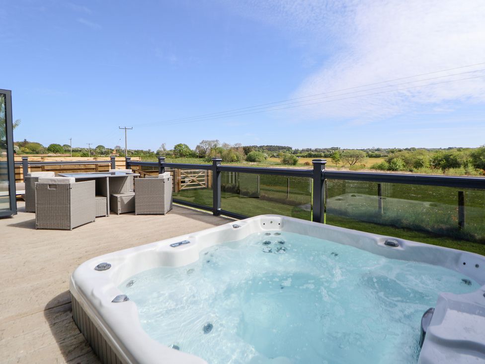 A hot tub with chairs and a table on a deck at The Lodge @ Racecourse House Babell near Holywell