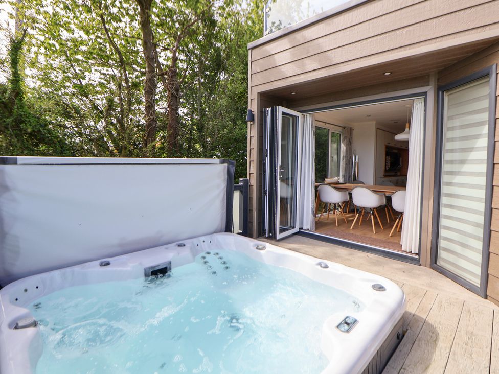 An outdoor area with a hot tub and an open entrance to a dining area at The Lodge @ Racecourse House, Babell near Holywell