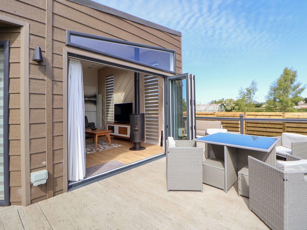 An outdoor terrace with seating and open sliding doors at The Lodge @ Racecourse House Babell near Holywell