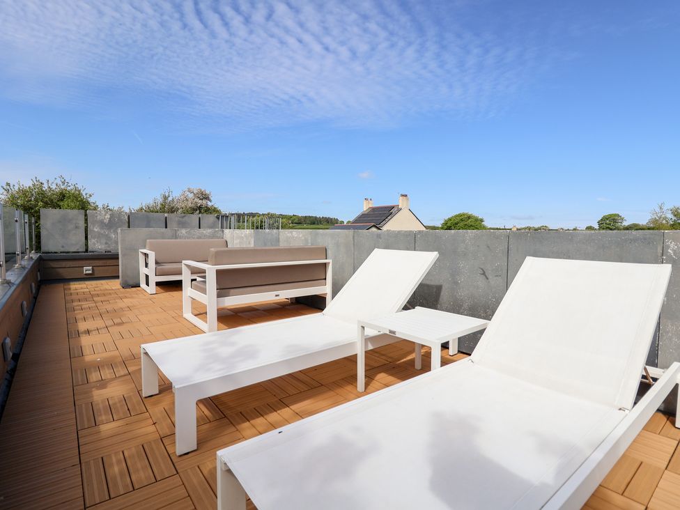 A roof terrace with sun loungers and an outdoor sofa at The Lodge @ Racecourse House in Babell near Holywell