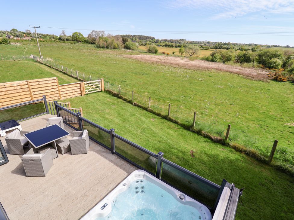 An outdoor space with a hot tub and dining area at The Lodge @ Racecourse House Babell near Holywell