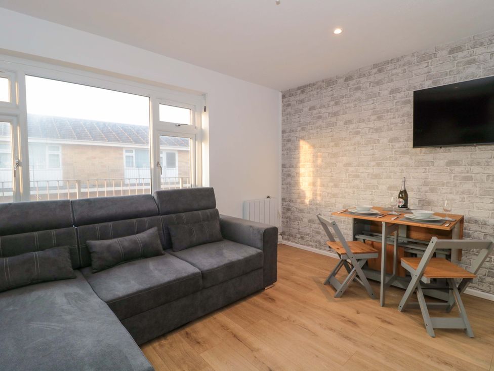 A living room with a sofa and dining area at Flat 24 in Brean