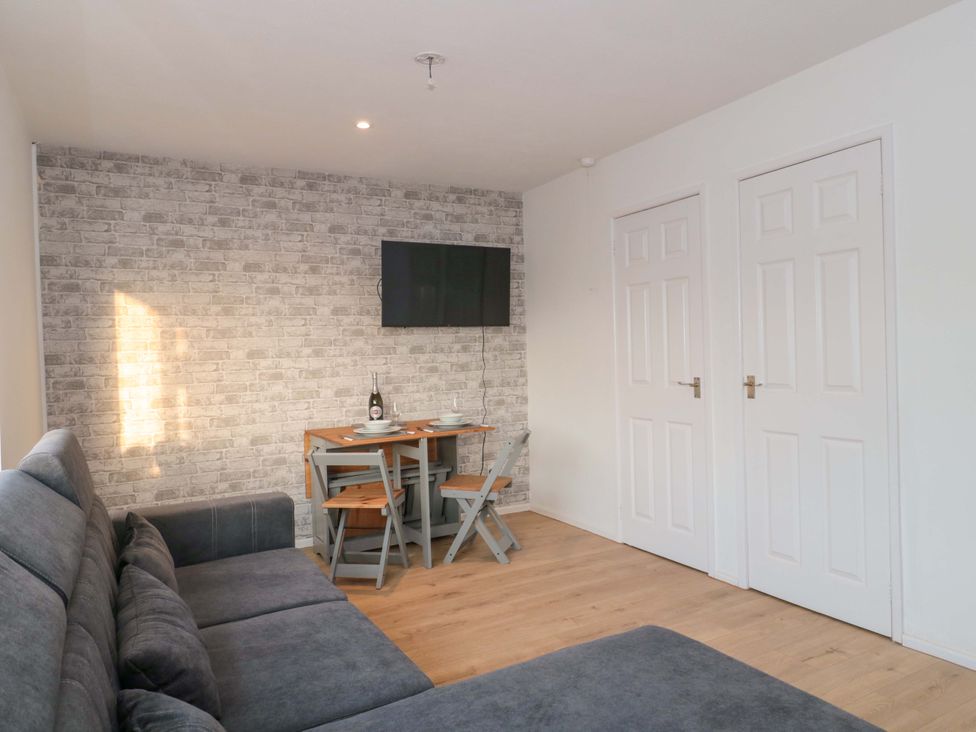 A living room with a sofa, table, chairs, and television at Flat 24 in Brean