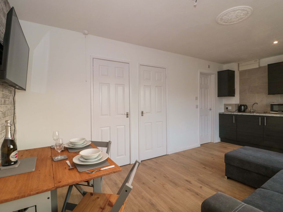 A living room with a table and chairs and a television at Flat 24 in Brean