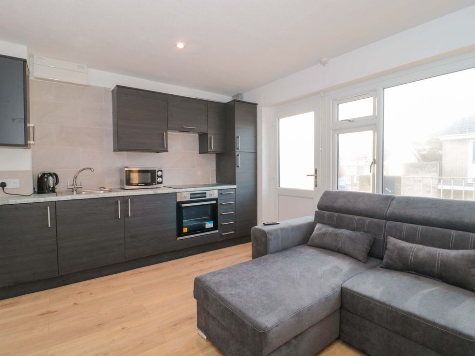 A kitchen with cabinets and a sofa at Flat 24 in Brean