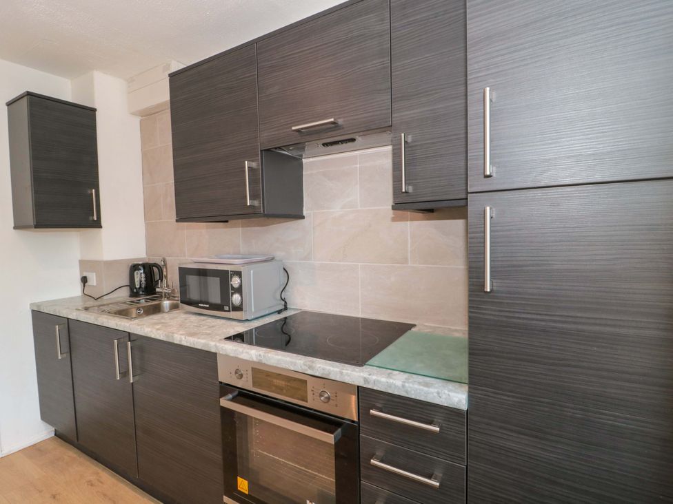 A kitchen with cabinets, sink, kettle, microwave, and stove at Flat 24 Brean