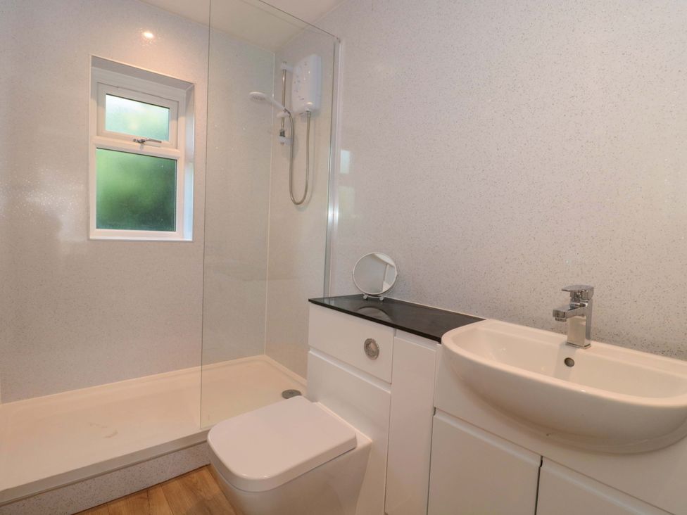 A bathroom featuring a shower, toilet, and sink at Flat 24 in Brean