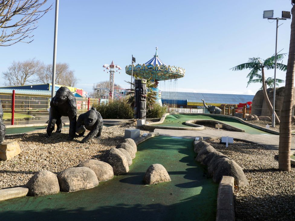 An outdoor mini golf course with gorilla statues and a carousel at Flat 24 in Brean