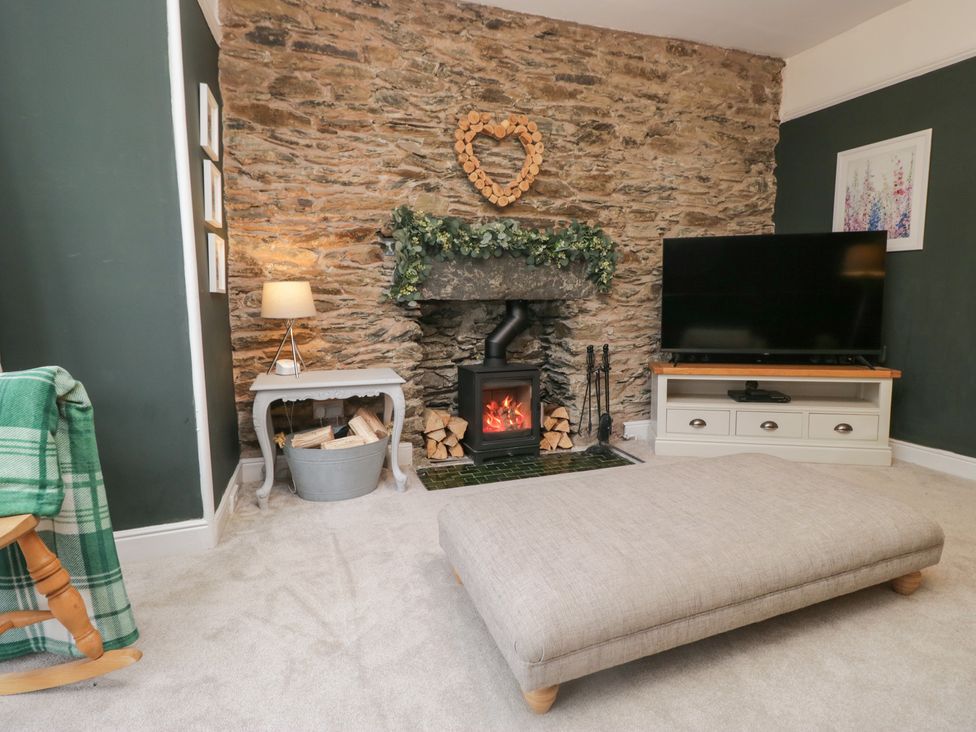 A living room with a stone wall and fireplace at The Wonky Nest in Bowness-On-Windermere