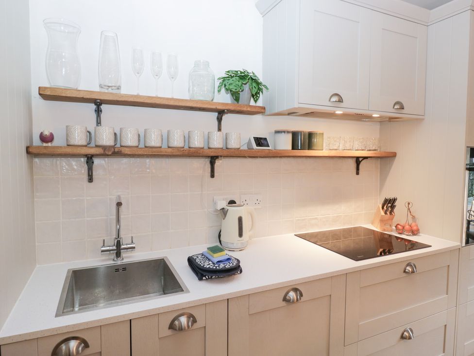 A kitchen with shelves containing mugs and glasses at The Wonky Nest in Bowness-On-Windermere