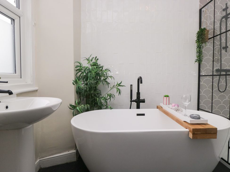 A bathroom with a bath tub and sink at The Wonky Nest in Bowness-On-Windermere
