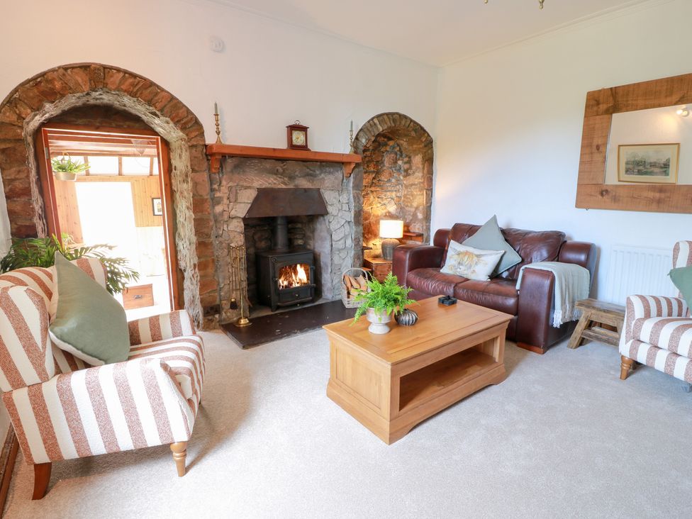 A living room with a fireplace and seating area at Balsaggart Farm