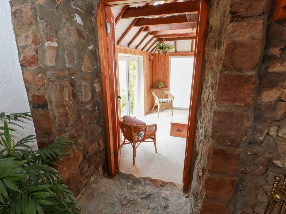 A snug with a stone wall and a door leading to a chair at Balsaggart Farm 