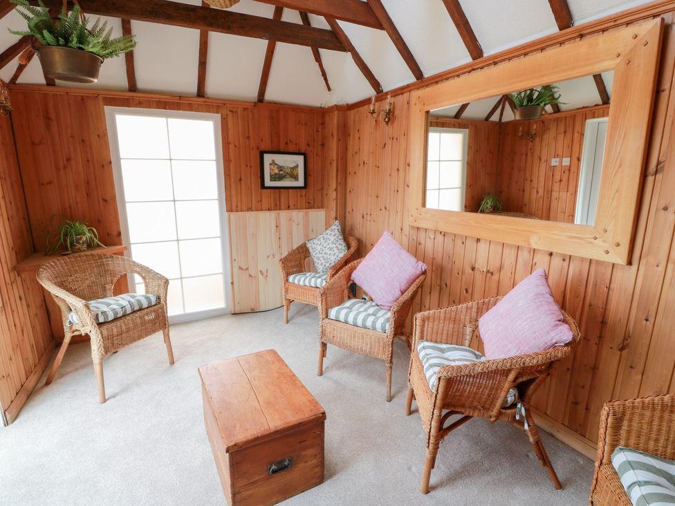 A snug with wicker chairs and a wooden table at Balsaggart Farm