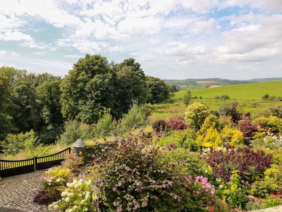 A garden with flowers and trees overlooking hills at Balsaggart Farm