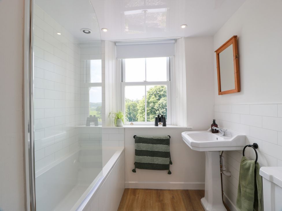 A bathroom with a bathtub, sink and window at Balsaggart Farm in 