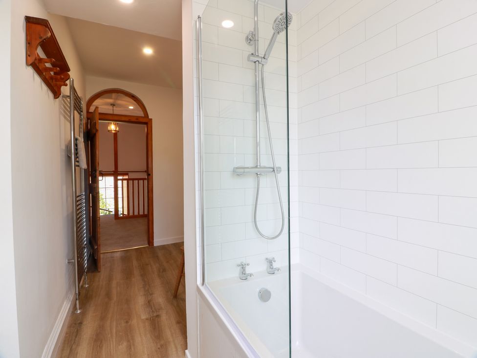 A bathroom featuring a bathtub with shower and a towel radiator at Balsaggart Farm