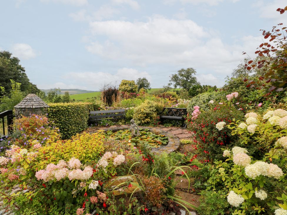 A garden with flowers and a bench at Balsaggart Farm