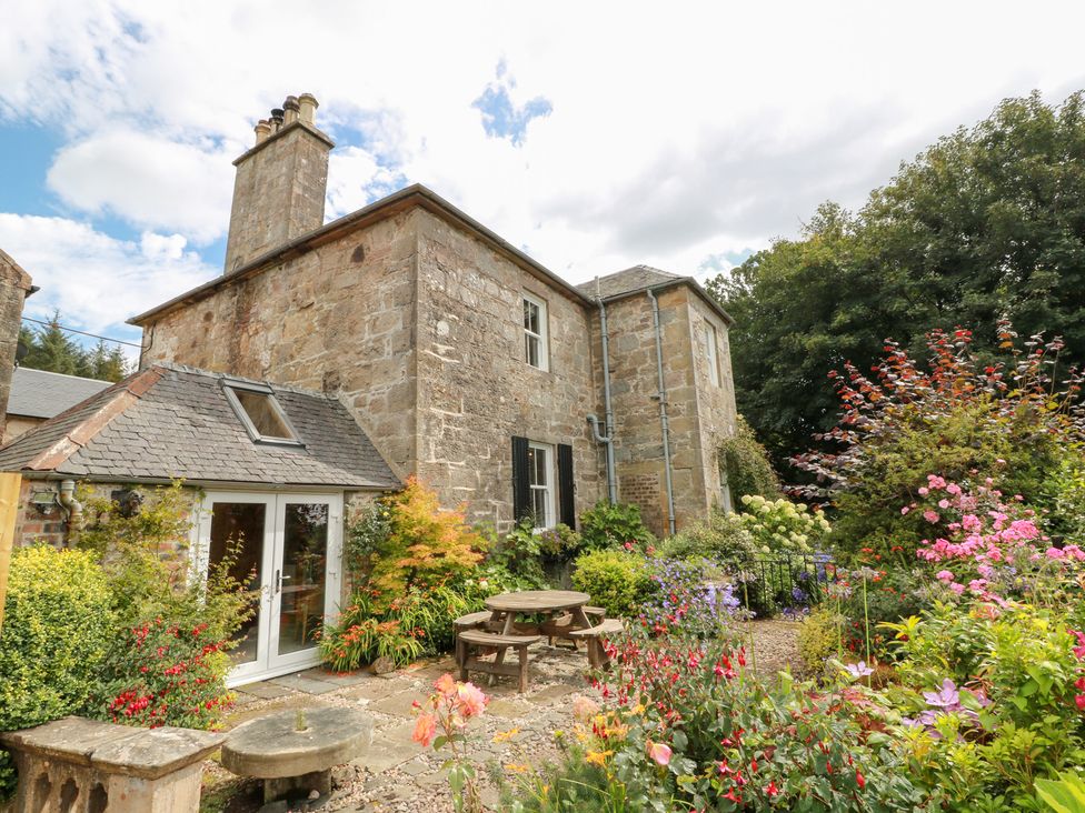 A house with garden seating and flowers at Balsaggart Farm in 