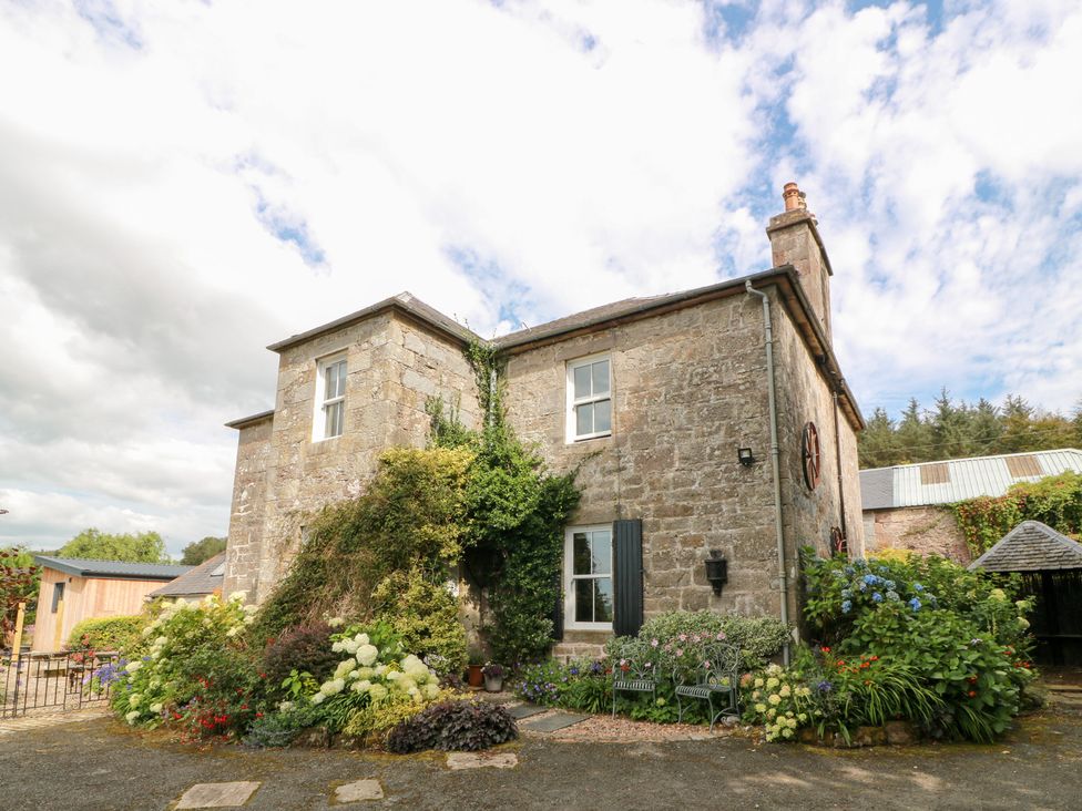 A stone building with flowers and seating area at Balsaggart Farm 