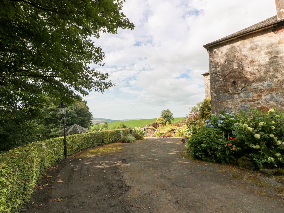 An outdoor driveway with a lamp post and flowers at Balsaggart Farm