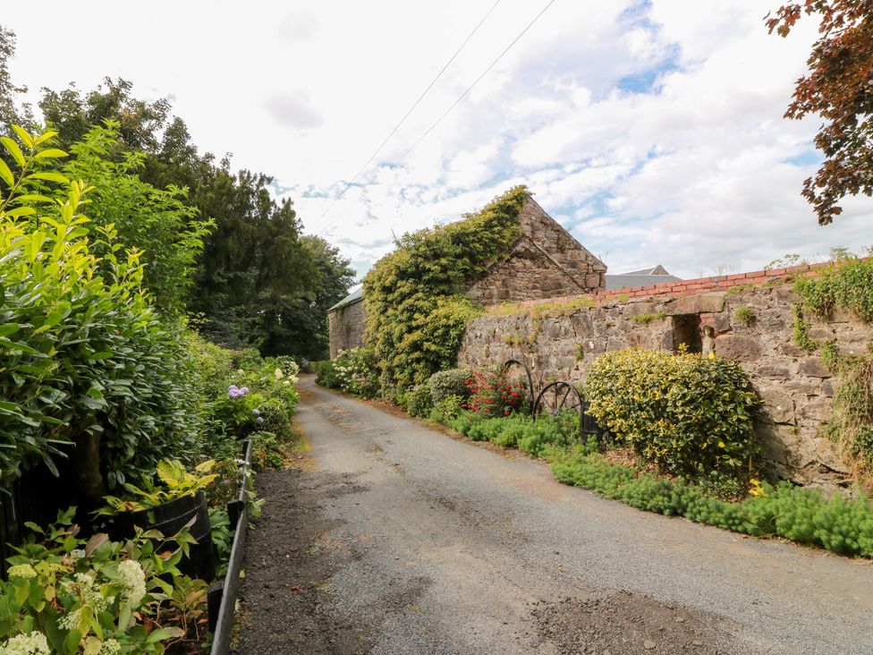 A gravel road with greenery and stone walls at Balsaggart Farm
