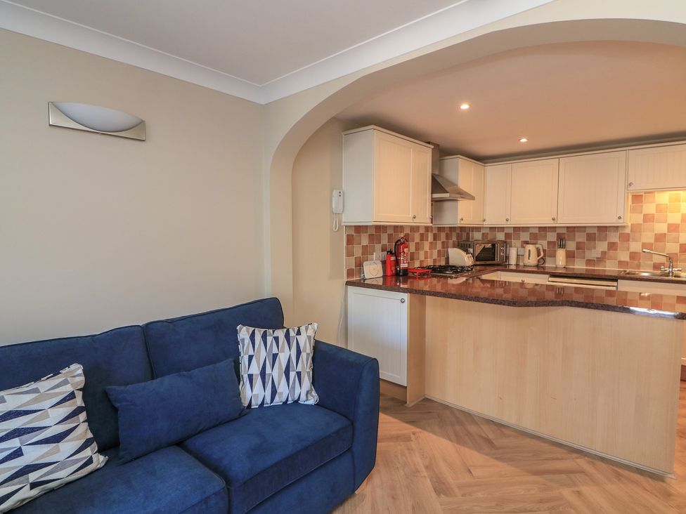 A living room with a sofa and open kitchen area at 6 Dartmouth House in Dartmouth