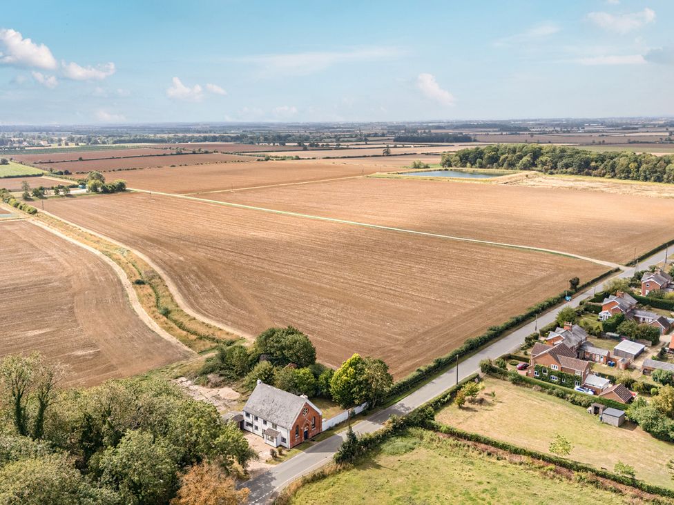 An aerial view of fields and a farmhouse near residential homes at The Old Chapel in Glentworth near Ingham