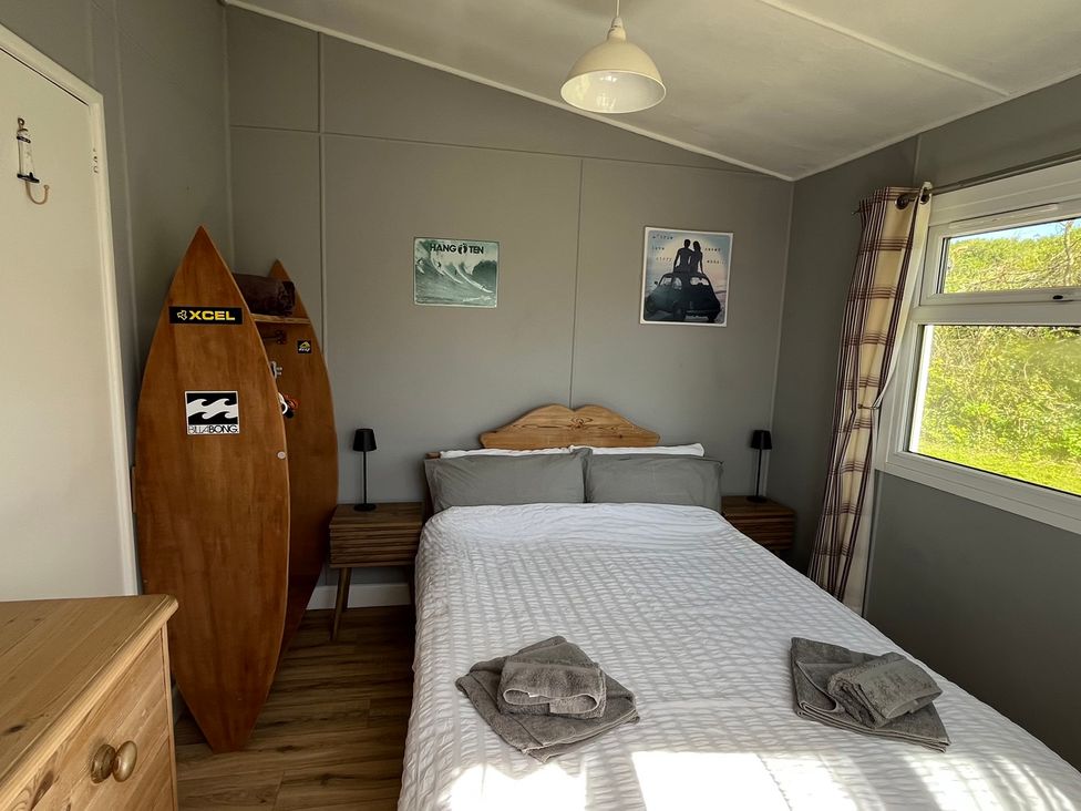 A bedroom with a bed and surfboards at Chalet 3 Wipeout in Hayle