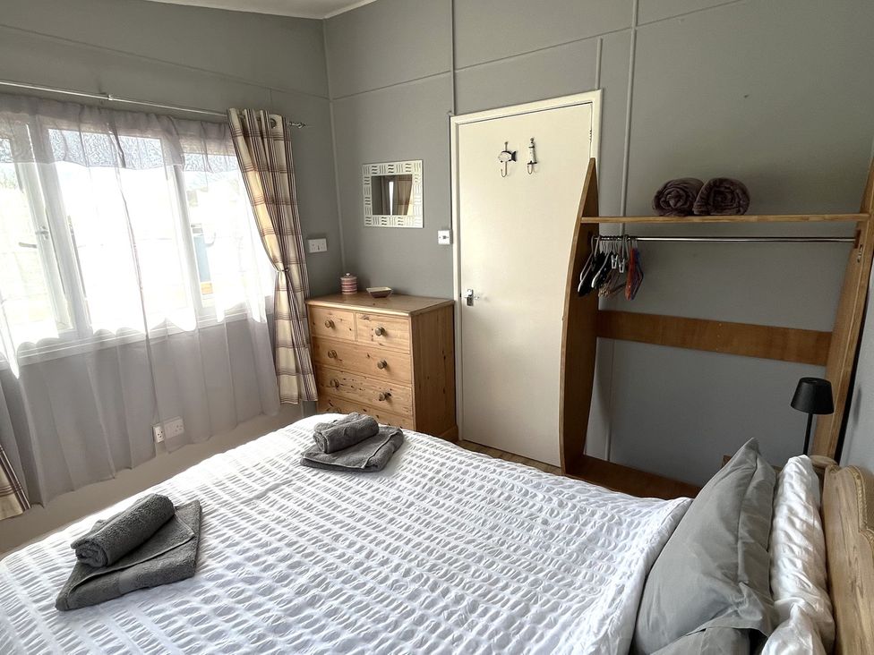 A bedroom with a bed and furniture at Chalet 3 Wipeout Hayle