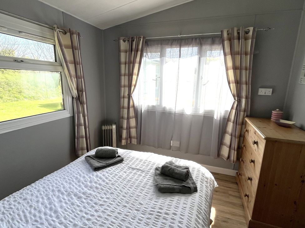 A bedroom with a bed and towels on top at Chalet 3 Wipeout in Hayle