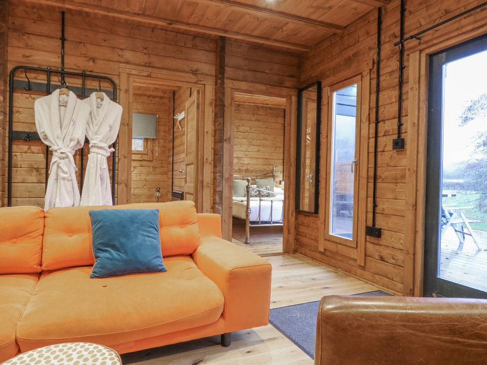 A living room with a sofa and robes hanging at Bee Hive South Luffenham near Edith Weston