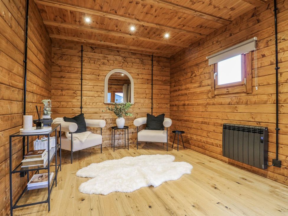 A cozy sitting area with wooden walls and a mirror at Badger's Burrow in Edith Weston