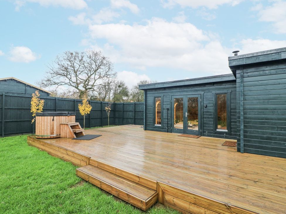 An outdoor deck with a hot tub at Badger's Burrow Edith Weston