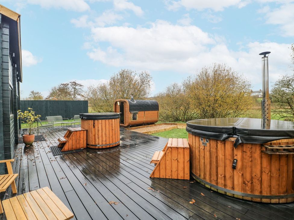 An outdoor area with a hot tub and barrel sauna at Badger's Burrow in Edith Weston