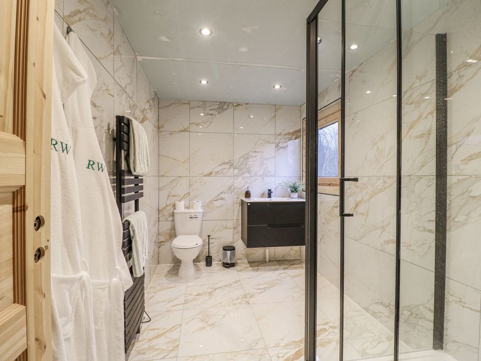 A bathroom with shower, toilet, sink, and towels at Badger's Burrow in Edith Weston