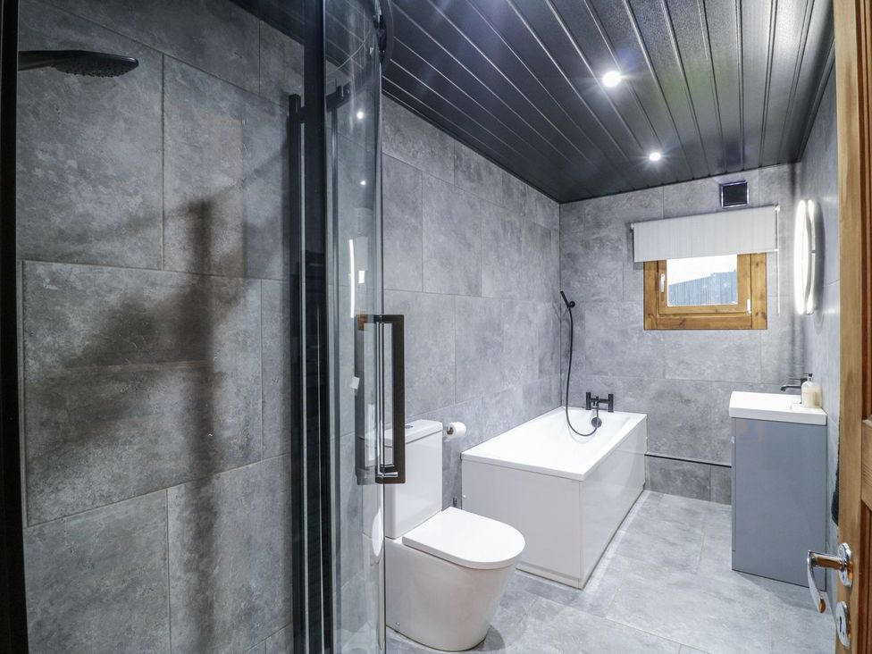A bathroom with a shower, bathtub, toilet, and sink at Badger's Burrow in Edith Weston