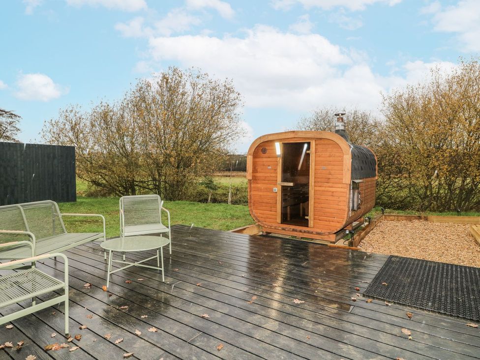 A garden with a wooden sauna and seating area at Badger's Burrow Edith Weston