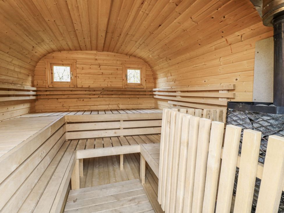 A sauna with wooden benches and stove at Badger's Burrow in Edith Weston
