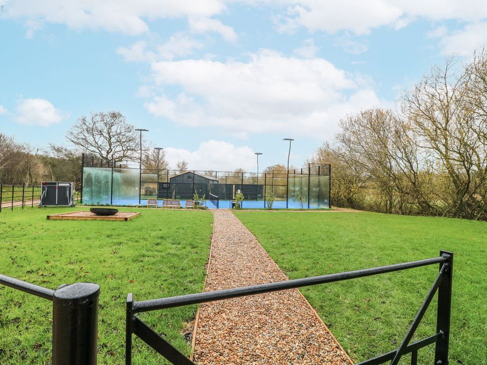 An outdoor area with a pathway and tennis court at Badger's Burrow in Edith Weston