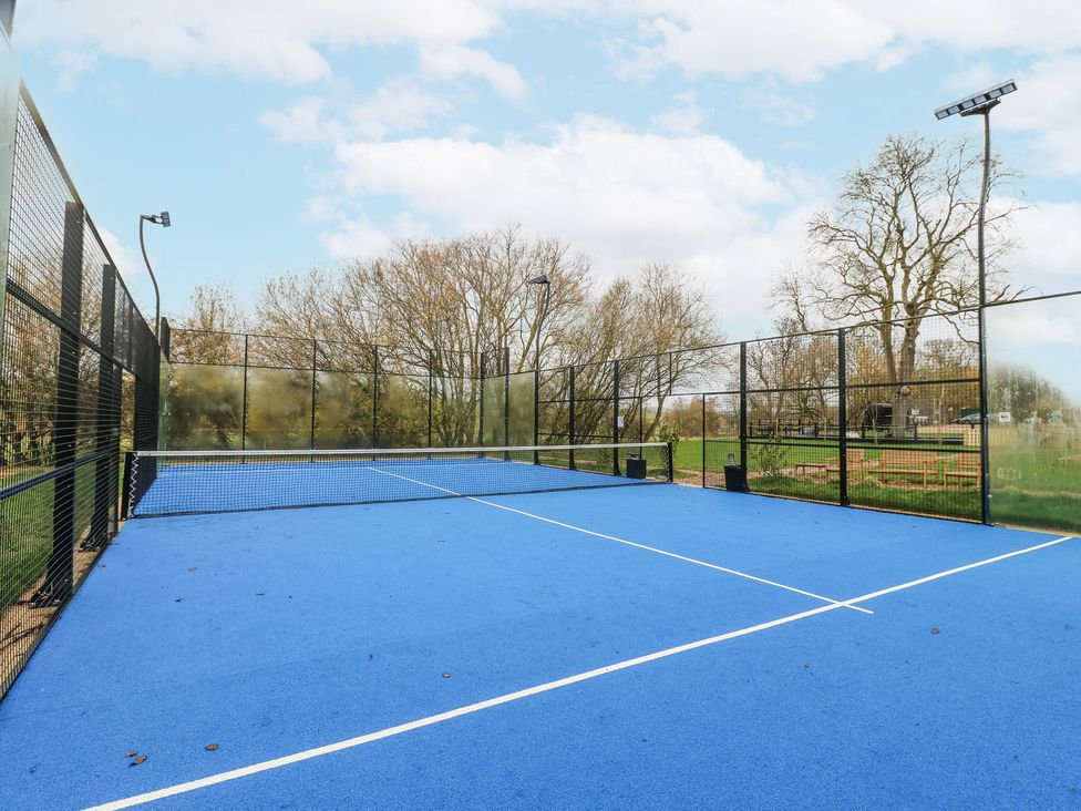 A tennis court with a blue surface and net at Badger's Burrow in Edith Weston