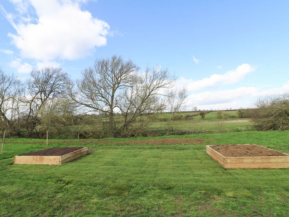 A garden with raised beds and grass at Badger's Burrow in Edith Weston