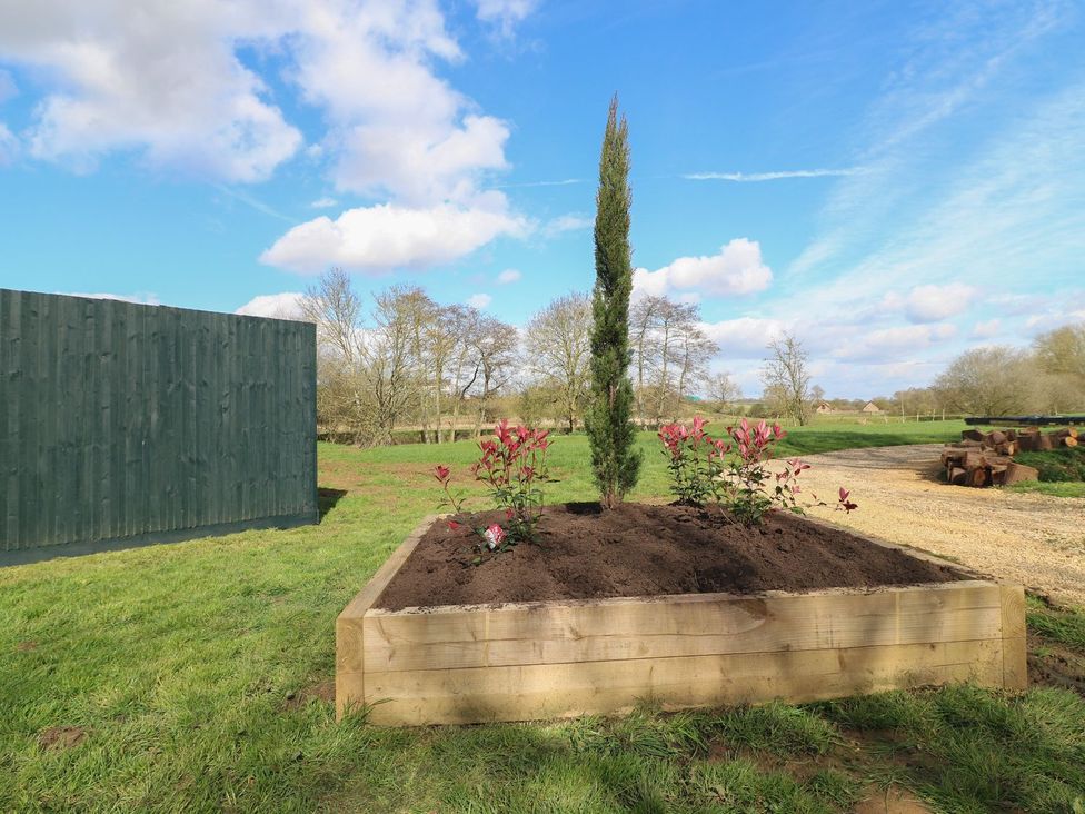 A wooden planter with flowers and a cypress tree at Badger's Burrow in Edith Weston