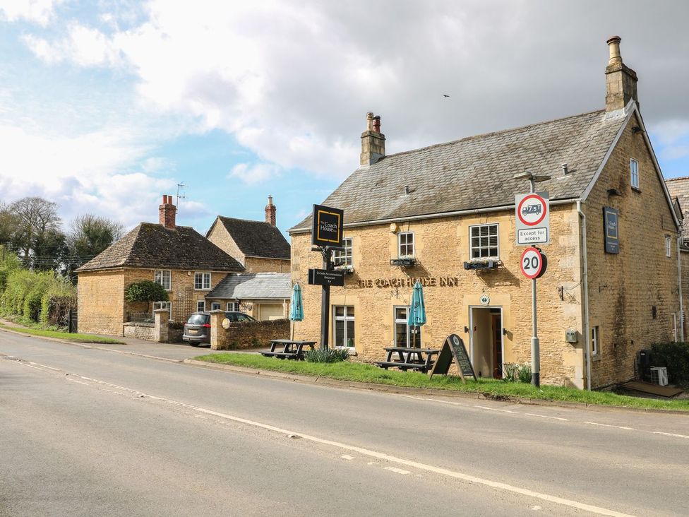 A pub with a sign in front and houses nearby at Badger's Burrow in Edith Weston