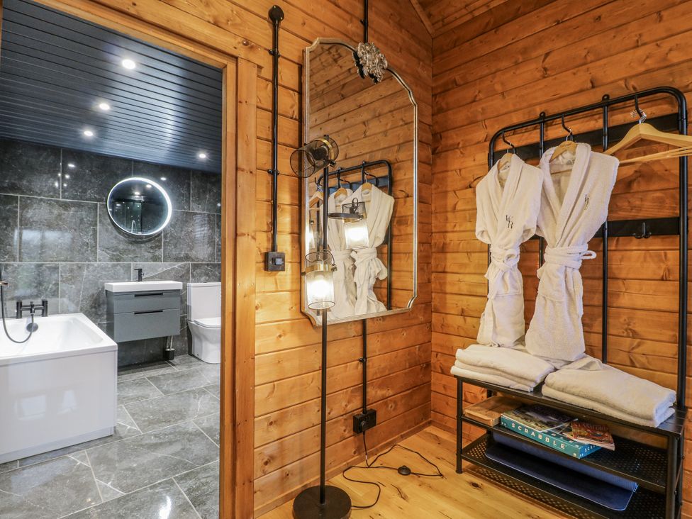A bathroom with a bathtub and towels in a wooden cabin at Rabbit Hole near Stamford