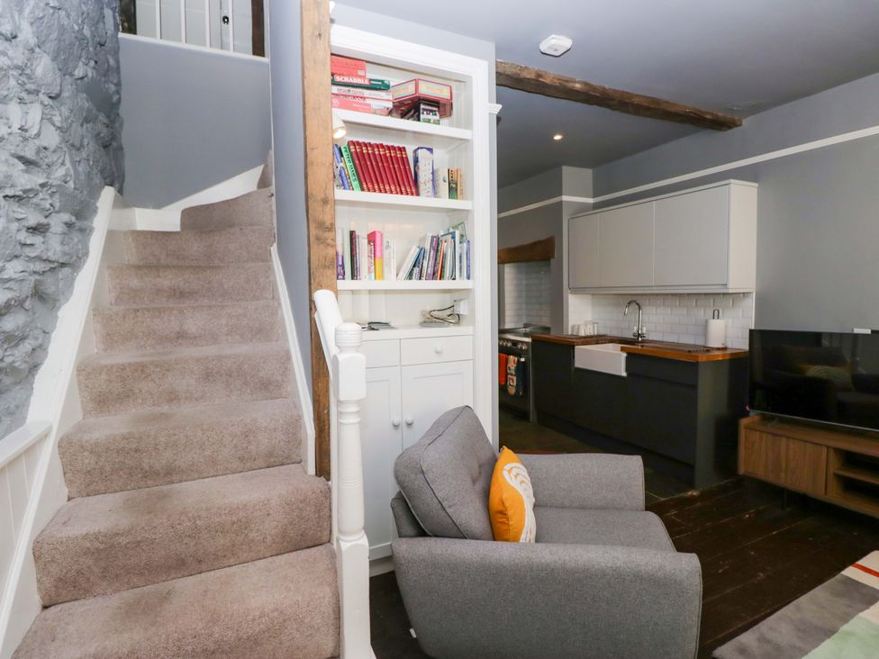 A living room with a staircase and kitchen area at Unicorn Cottage 